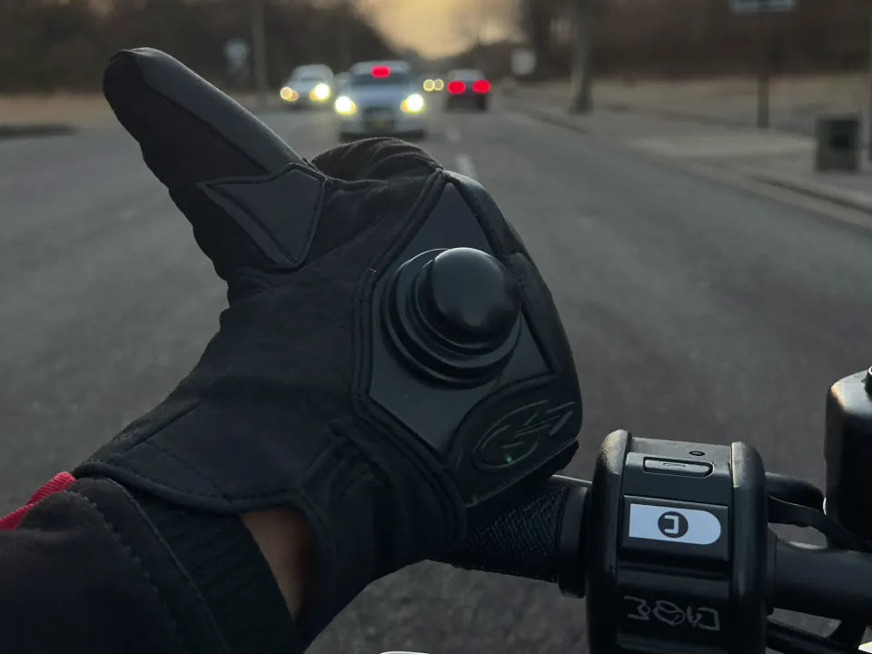 A gloved thumb pressing the heat button at a red light